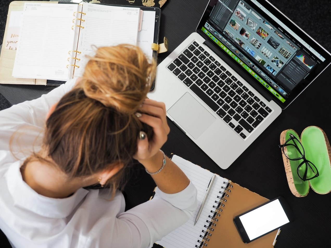 Mevrouw aan bureau met daarop laptop, agenda en kladblok